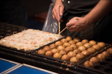 Takoyaki toplarını yemek çubuklarıyla hazırlayan kişi.