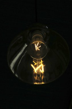 Camdan lamba gölgesinde parlayan eski model ampul teli.