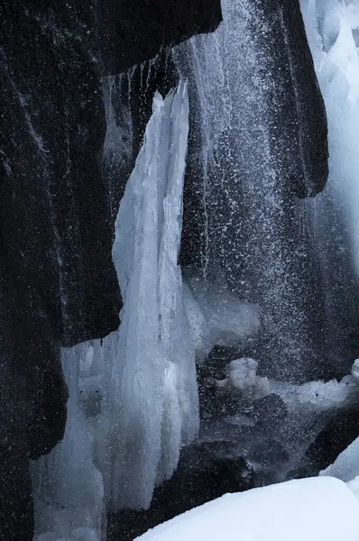 a waterfall with ice and snow on the ground