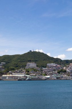 Okyanus, dağlar, mavi gökyüzü ve Nagasaki Limanı Feribot Terminali. Japonya