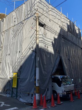 Yakınlarda park etmiş gri muşambalarla kaplı büyük bir bina.