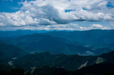 Sabah, bulutların mavi gökyüzünde olduğu güzel karanlık dağlar manzarası.