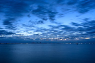 Ufukta deniz ve şehir üzerinde güzel bir gün batımı beliriyor.      