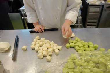 Erkek aşçı mutfakta yemek pişiriyor, mantı yapıyor. 