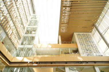 Camdan duvarları olan modern avluda ahşap kirişler tavandan süzülüyor.