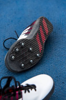 Mavi arka planda siyah spor ayakkabılar.