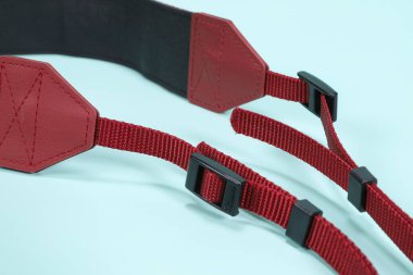 Kırmızı kamera kayışı açık mavi arkaplanda düz yatıyor