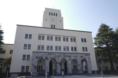 Kemerli giriş ve taş cepheli uzun beyaz bina.