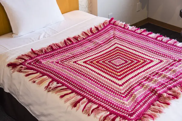 pink and red blanket on bed in hotel