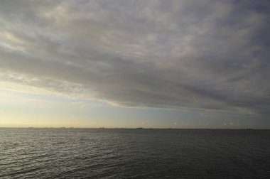 Ufukta deniz ve şehir üzerinde güzel bir gün batımı beliriyor.      