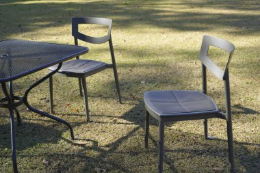 Açık masa ve yaz bahçesinde çimlerin üzerinde sandalyeler. 