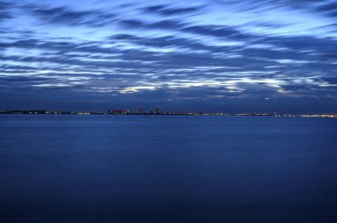 Ufukta deniz ve şehir üzerinde güzel bir gün batımı beliriyor.      