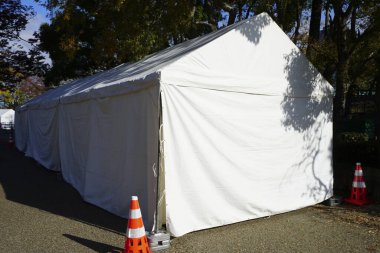 Beyaz çadır yapısı turuncu trafik konileriyle çevrili.