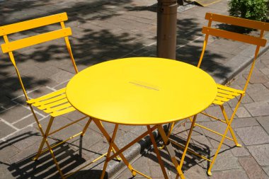 Sarı masa ve sandalyeler sokak kafesinde.