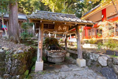 Geleneksel Japon arıtma çeşmesi ahşap çatı yapısının altında.