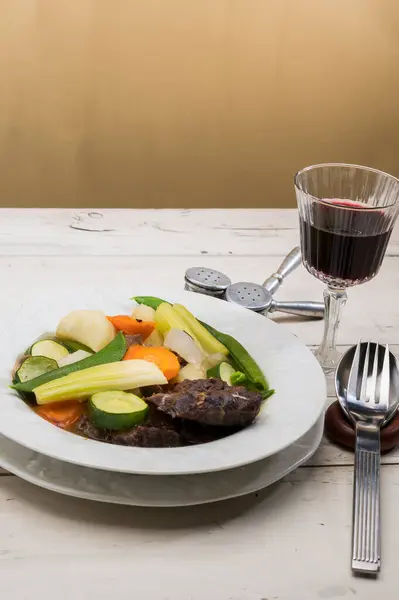 wine and stewed meat with vegetables on white plate