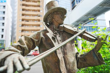 Şehir ilanlarına karşı keman çalan bir müzisyenin heykeli