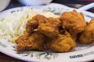 Kızarmış tavuk parçaları ve dilimlenmiş lahana tabağı. 