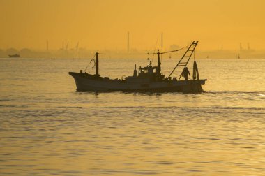 Güneşin doğuşunda balıkçı teknesiyle güzel bir deniz manzarası       