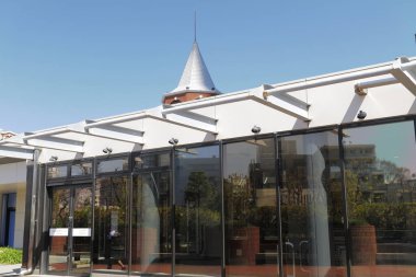 Mavi gökyüzünün altında konik çatısı olan modern cam bina.