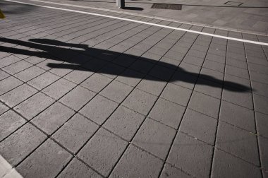 Kaldırımda yürüyen kişinin gölgeleri