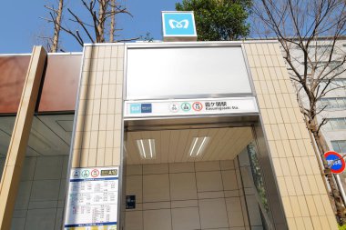 Modern metro girişi dış yüzeyinde fayanslı duvarlar ve ağaçlar var.