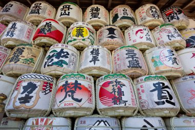 Renkli Japon kaligrafi tasarımları içeren dekoratif saki fıçıları.