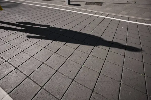 Kaldırımda yürüyen kişinin gölgeleri