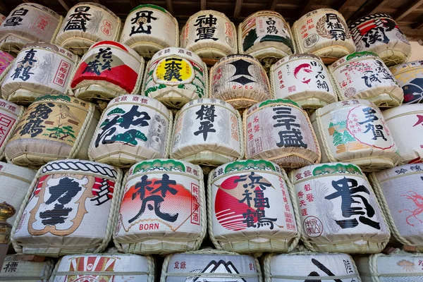 Renkli Japon kaligrafi tasarımları içeren dekoratif saki fıçıları.