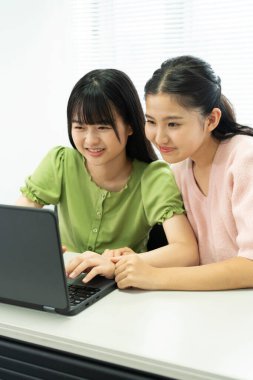 Laptop bilgisayarında çalışan iki genç Asyalı kız öğrenci..