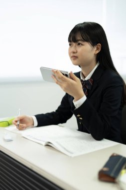 Çağdaş bir sınıf ortamında okuyan genç bir Japon öğrenci resmediliyor..