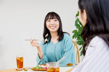 İki genç Japon kadın restoranda yemek yiyor.