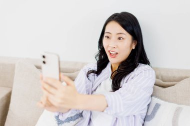 Akıllı telefondan video görüşmesi yapan güzel bir Japon kadın.