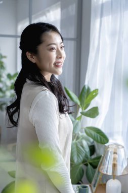 Evinde pencerenin önünde duran kadın.