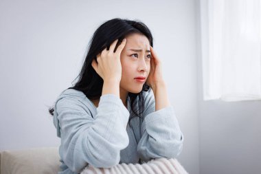 Evde baş ağrısı çeken Asyalı genç bir kadın.