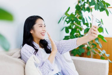 Akıllı telefondan video görüşmesi yapan güzel bir Japon kadın.