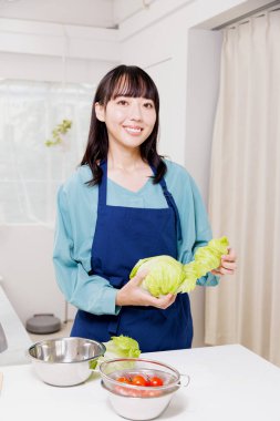 Elinde yeşil lahana tutan güzel bir Japon kadın.