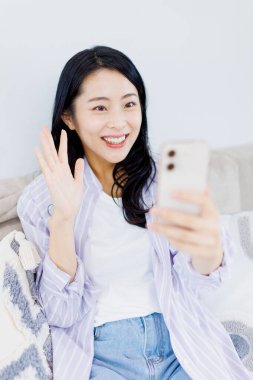 Akıllı telefondan video görüşmesi yapan güzel bir Japon kadın.