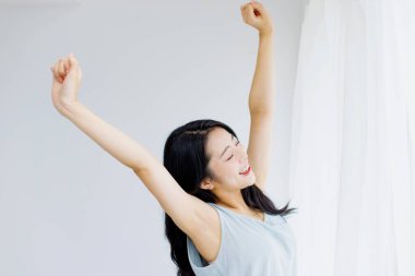 Mutlu Asyalı kadın odada dinleniyor, kollarını kaldır. 