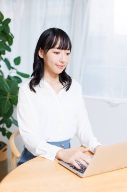 Genç Asyalı iş kadını evde dizüstü bilgisayar kullanıyor..