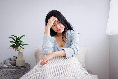 Evde baş ağrısı çeken Asyalı genç bir kadın.