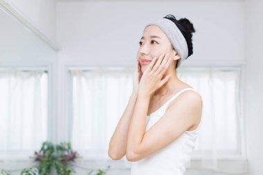 Güzel Asyalı kadın yüzüne dokunuyor. Cilt bakımı kavramı