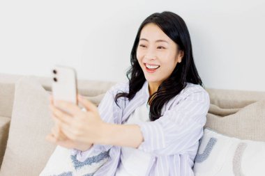 Akıllı telefondan video görüşmesi yapan güzel bir Japon kadın.