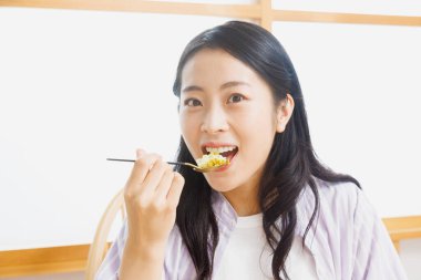 Genç Asyalı kadın Japon yemeği yiyor.