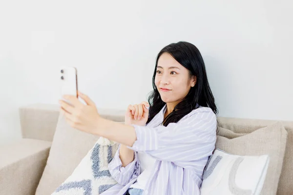 Beautiful Japanese woman having video call through smartphone