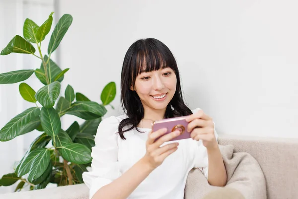 Glimlachende Aziatische Vrouw Zitten Thuis Met Behulp Van Mobiele Telefoon — Stockfoto