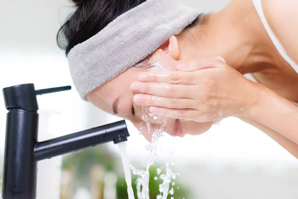 Asian woman washing face with her hands