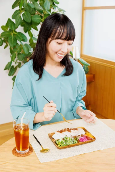 Asian woman eating sushi in restaurant