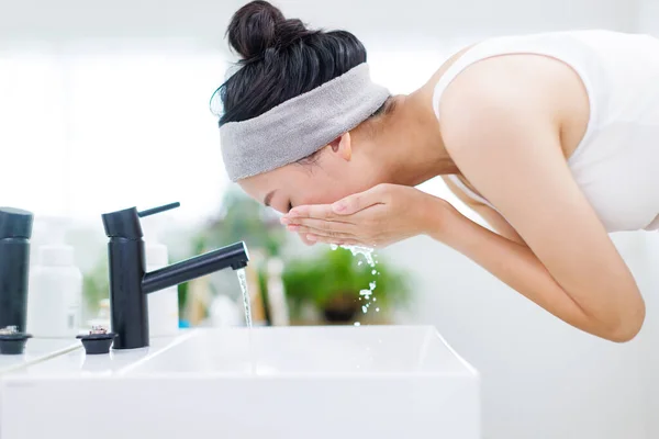 Asian woman washing face with her hands