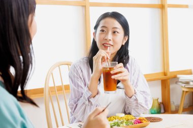 İki genç Japon kadın restoranda yemek yiyor.
